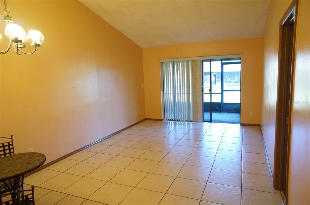 An empty room with orange walls, beige tile flooring, and a sliding glass door — 104 CREEKSIDE WAY, ORLANDO, FL