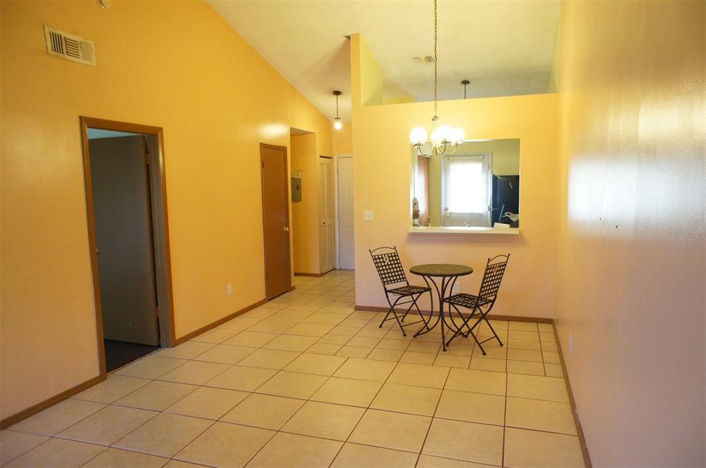 A dining area with tile floors, yellow walls, and a pass-through window to the kitchen — 104 CREEKSIDE WAY, ORLANDO, FL
