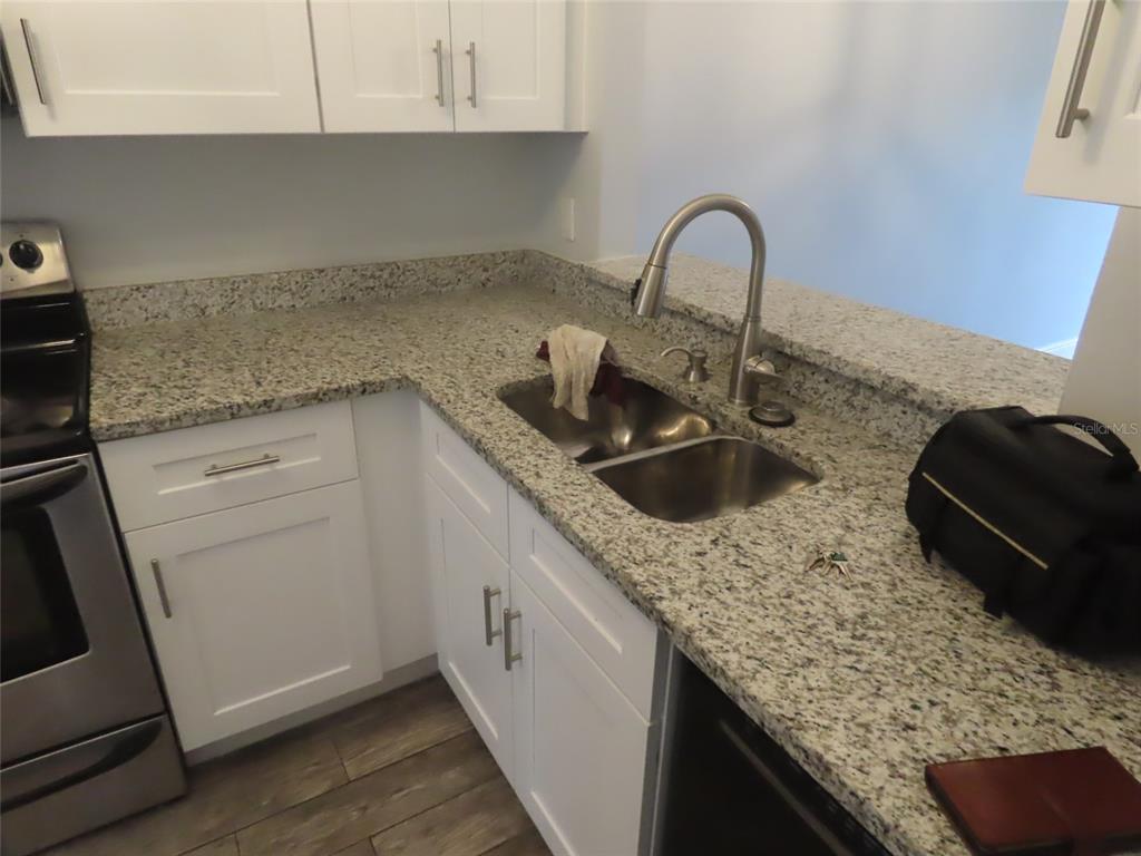 A kitchen features white cabinets, granite countertops, a stainless steel sink, and stainless steel appliances — 104 CREEKSIDE WAY, ORLANDO, FL