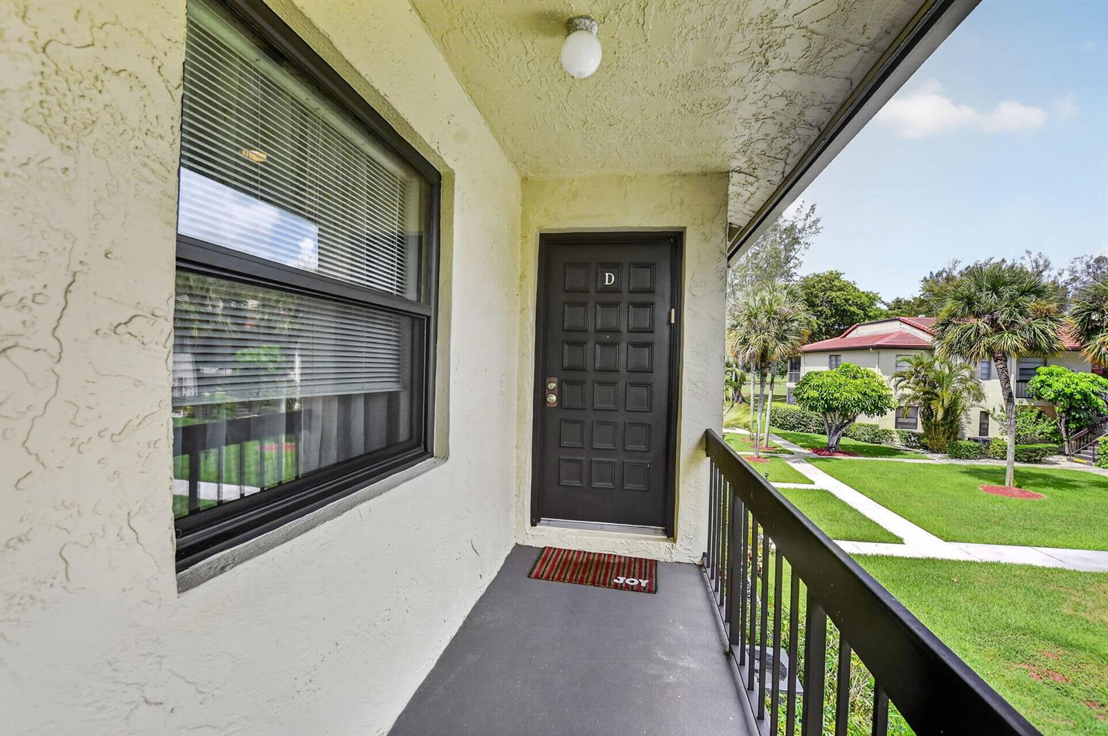 An exterior view of a balcony with a dark door marked D and a window — 8310 Casa Del Lago # D, Boca Raton FL 33433, BOCA RATON, FL