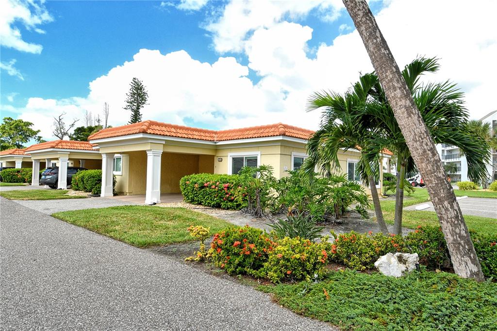 A single-story villa with a tan stucco exterior, orange tile roof, and a covered carport — 4780 GULF OF MEXICO DR. VILLA 5, LONGBOAT KEY, FL