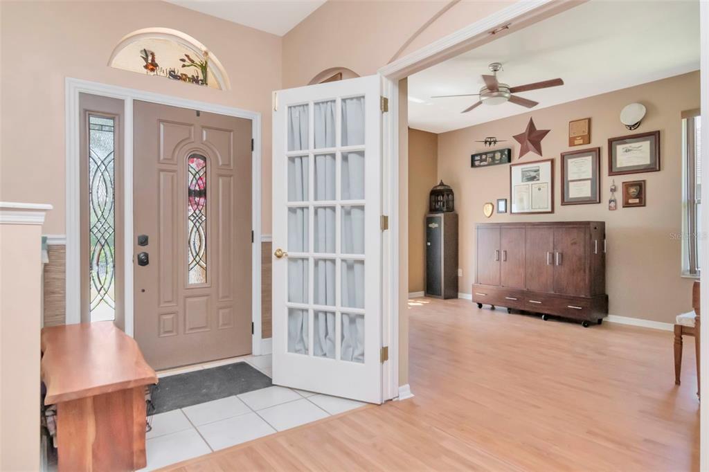 An entryway features a tan front door, a white French door, and light wood flooring — 19103 WIND DANCER STREET, LUTZ, FL