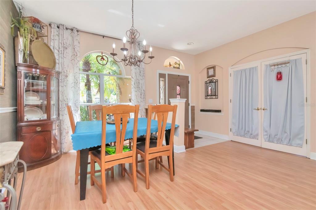 A dining room with light wood flooring, a blue-covered table, and a decorative chandelier — 19103 WIND DANCER STREET, LUTZ, FL