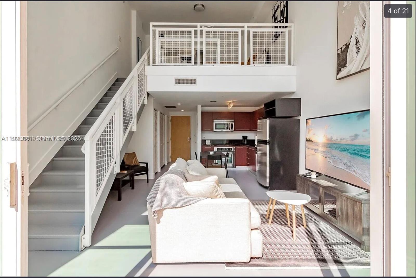 A living room with a staircase, loft area, and an open kitchen with dark cabinets — 253 NE 2nd St # 617, Miami FL 33132, MIAMI, FL