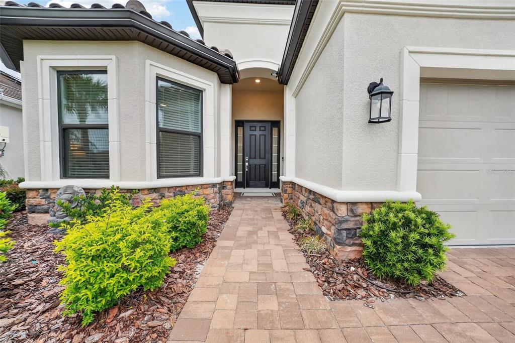The exterior of a house features a paved walkway leading to a black front door — 5312 CASERTA COURT, PALMETTO, FL