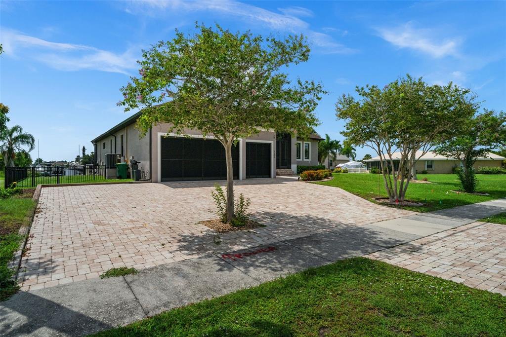 A single-story house with a paved driveway, a three-car garage, and two trees in front — 4286 HARBOR BOULEVARD, PORT CHARLOTTE, FL