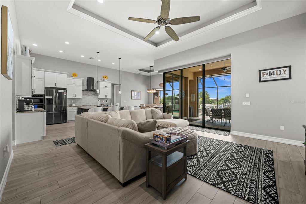 An open-concept living room and kitchen feature a sectional sofa, tray ceiling, and sliding doors — 4286 HARBOR BOULEVARD, PORT CHARLOTTE, FL