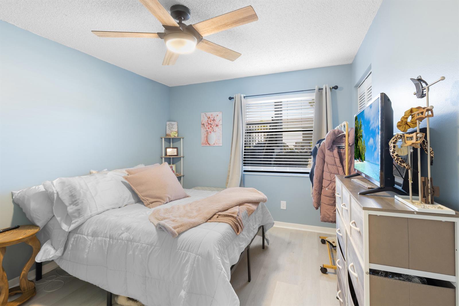 A bedroom features light blue walls, a ceiling fan, a bed, and a dresser with TV — 1270 SE Parkview Place # B5, Stuart FL 34994, STUART, FL