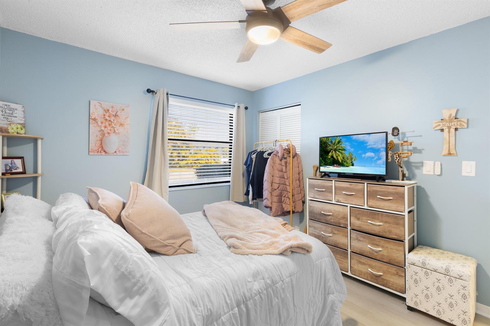 A bedroom features light blue walls, a bed with white bedding, and a wooden dresser — 1270 SE Parkview Place # B5, Stuart FL 34994, STUART, FL