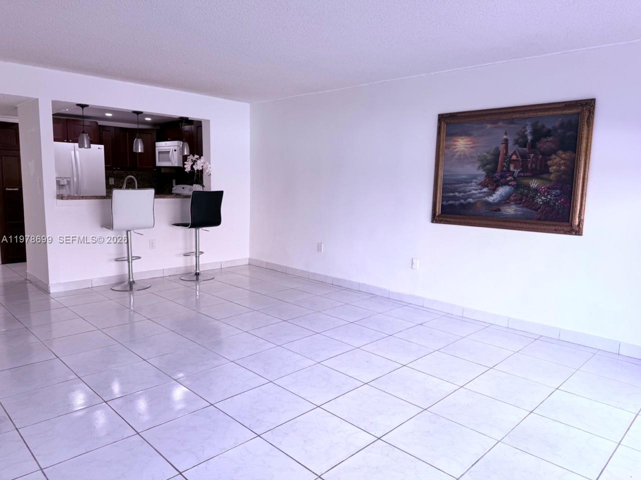 A tiled dining area features a breakfast bar with two stools and a framed painting — 15470 SW 82nd Ln # 316, Miami FL 33193, MIAMI, FL