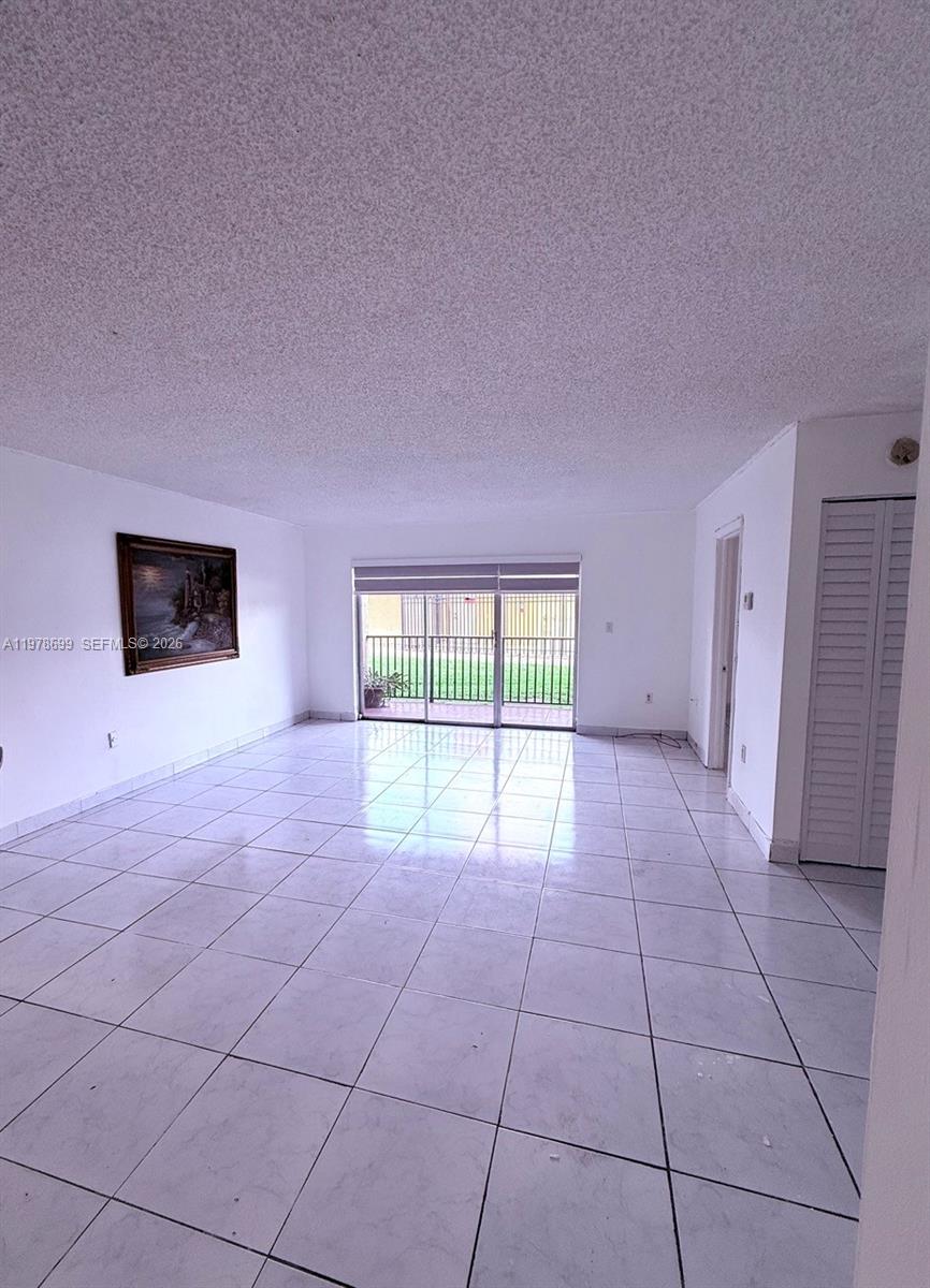 A bright, empty living room features white tile flooring and a sliding glass door — 15470 SW 82nd Ln # 316, Miami FL 33193, MIAMI, FL