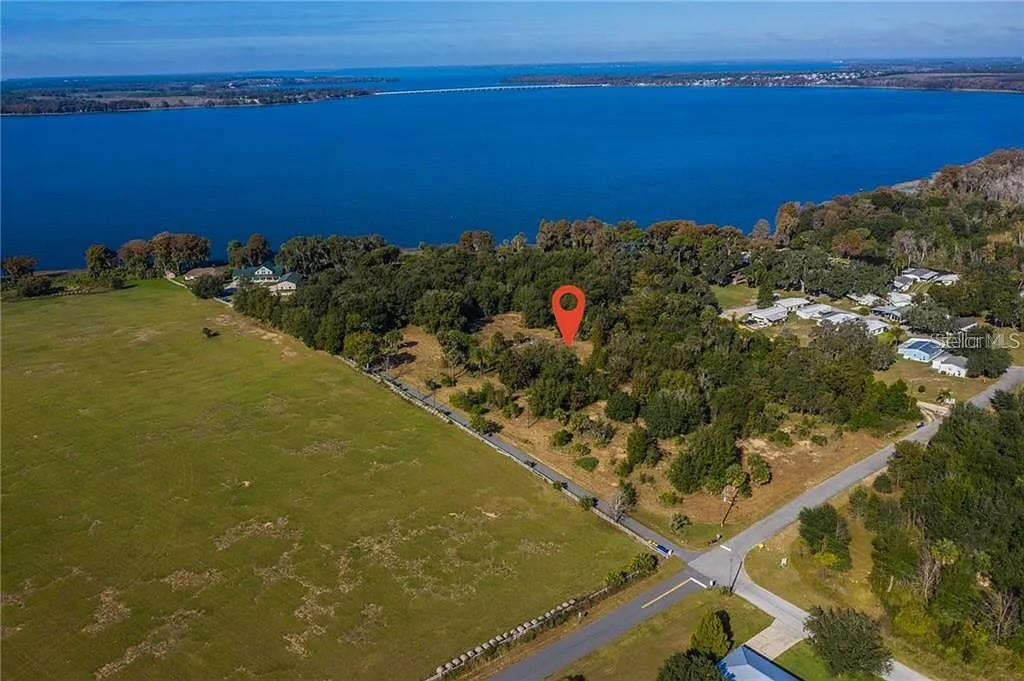 An aerial view shows a wooded lot marked with a pin near a large lake — 25800 WASHINGTON STREET, ASTATULA, FL