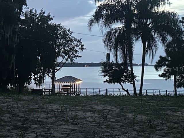 A boat dock sits on a lake at dusk with trees framing the water view — 25800 WASHINGTON STREET, ASTATULA, FL
