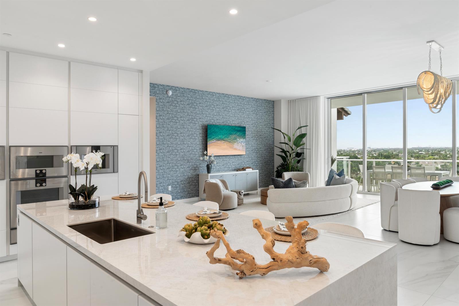 A modern open-concept kitchen and living area with white cabinetry, a blue accent wall, and balcony — 220 SE Mizner Boulevard, Boca Raton FL 33432, BOCA RATON, FL