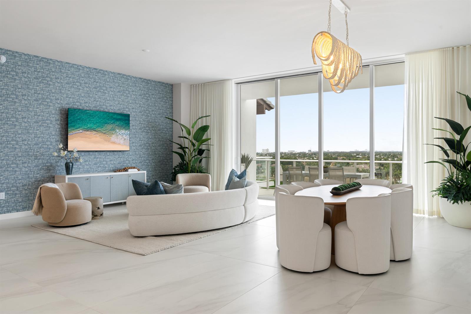 A modern living and dining area features a blue textured wall, curved sofa, and balcony — 220 SE Mizner Boulevard, Boca Raton FL 33432, BOCA RATON, FL