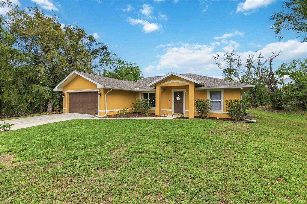 A single-story yellow house with a brown garage door and a covered front entryway — 2150 LITTLEFIELD LN, NORTH PORT, FL