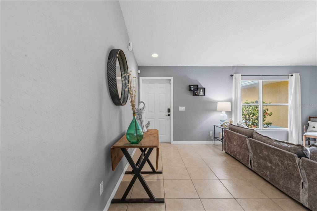 A living room features a console table, a grey sofa, and a white front door — 2150 LITTLEFIELD LN, NORTH PORT, FL