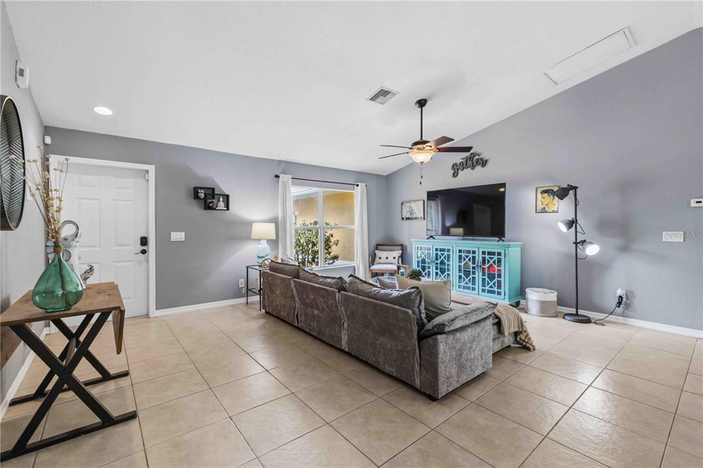 A living room with tile flooring, a gray sectional sofa, and a teal media console — 2150 LITTLEFIELD LN, NORTH PORT, FL