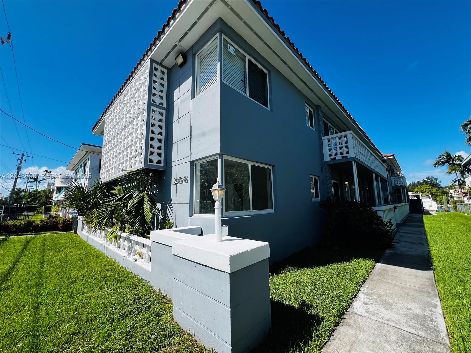 A two-story blue apartment building features decorative concrete screens and a sidewalk along the lawn — 2045 Calais Dr # 8, Miami Beach FL 33141, MIAMI BEACH, FL
