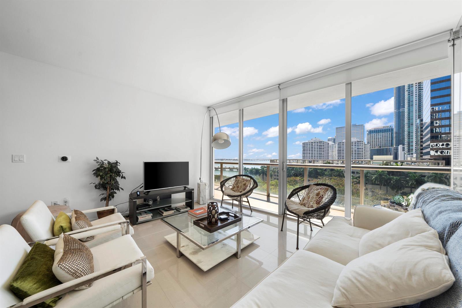 A modern living room features white furniture, a glass coffee table, and floor-to-ceiling windows — 495 Brickell Avenue # 811, Miami FL 33131, MIAMI, FL
