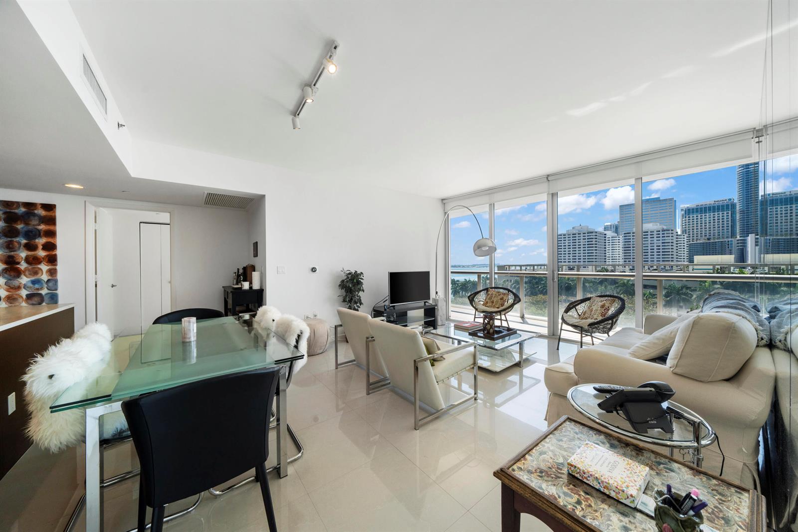 A modern living and dining area with floor-to-ceiling windows overlooking a city skyline — 495 Brickell Avenue # 811, Miami FL 33131, MIAMI, FL