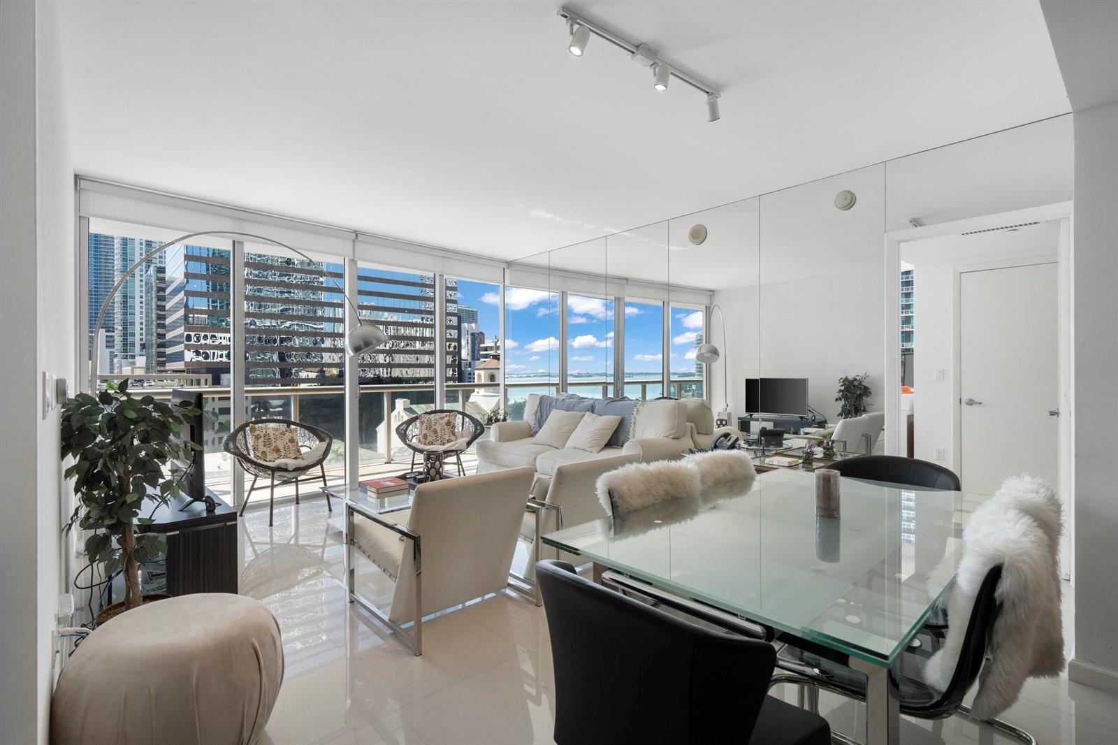 A bright living and dining area features floor-to-ceiling windows, mirrored walls, and city views — 495 Brickell Avenue # 811, Miami FL 33131, MIAMI, FL