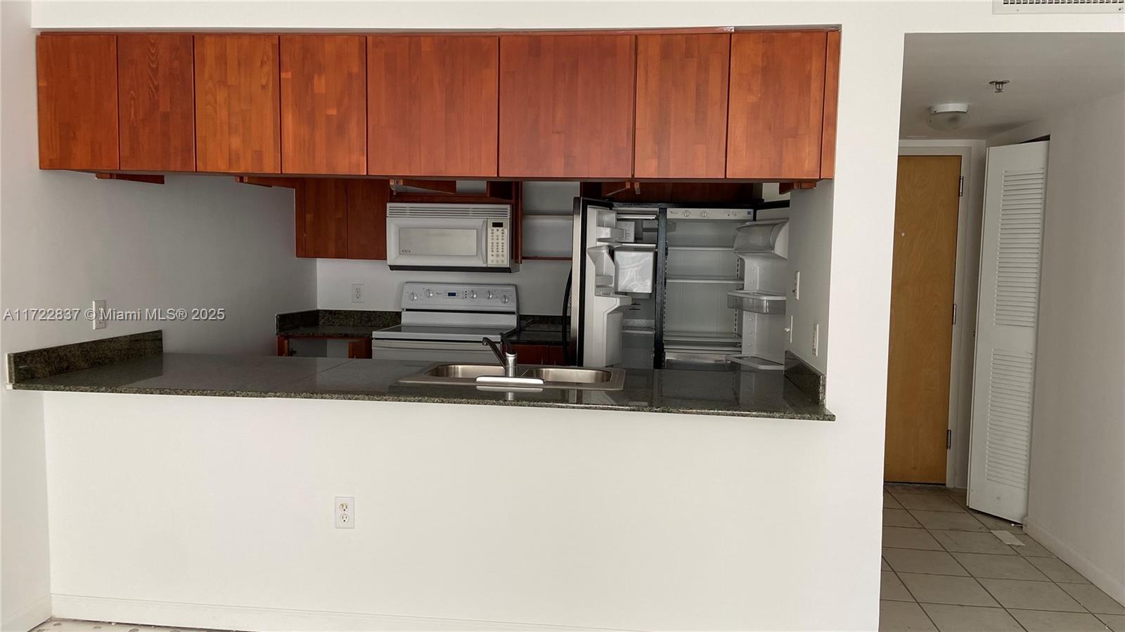 A kitchen features wooden cabinets, a granite countertop, and stainless steel appliances — 1200 Brickell Bay Dr # 2007, Miami FL 33131, MIAMI, FL