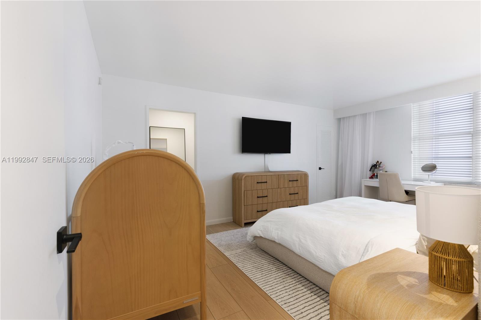 A bedroom features a bed, a wooden dresser, a television, and a wooden crib — 5161 Collins Ave # 410, Miami Beach FL 33140, MIAMI BEACH, FL
