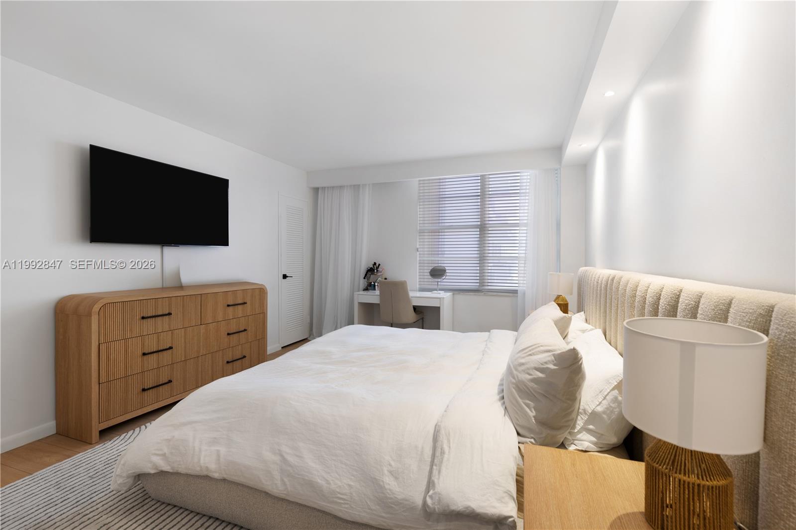 A bedroom features a bed with a textured headboard, a wooden dresser, and a desk — 5161 Collins Ave # 410, Miami Beach FL 33140, MIAMI BEACH, FL