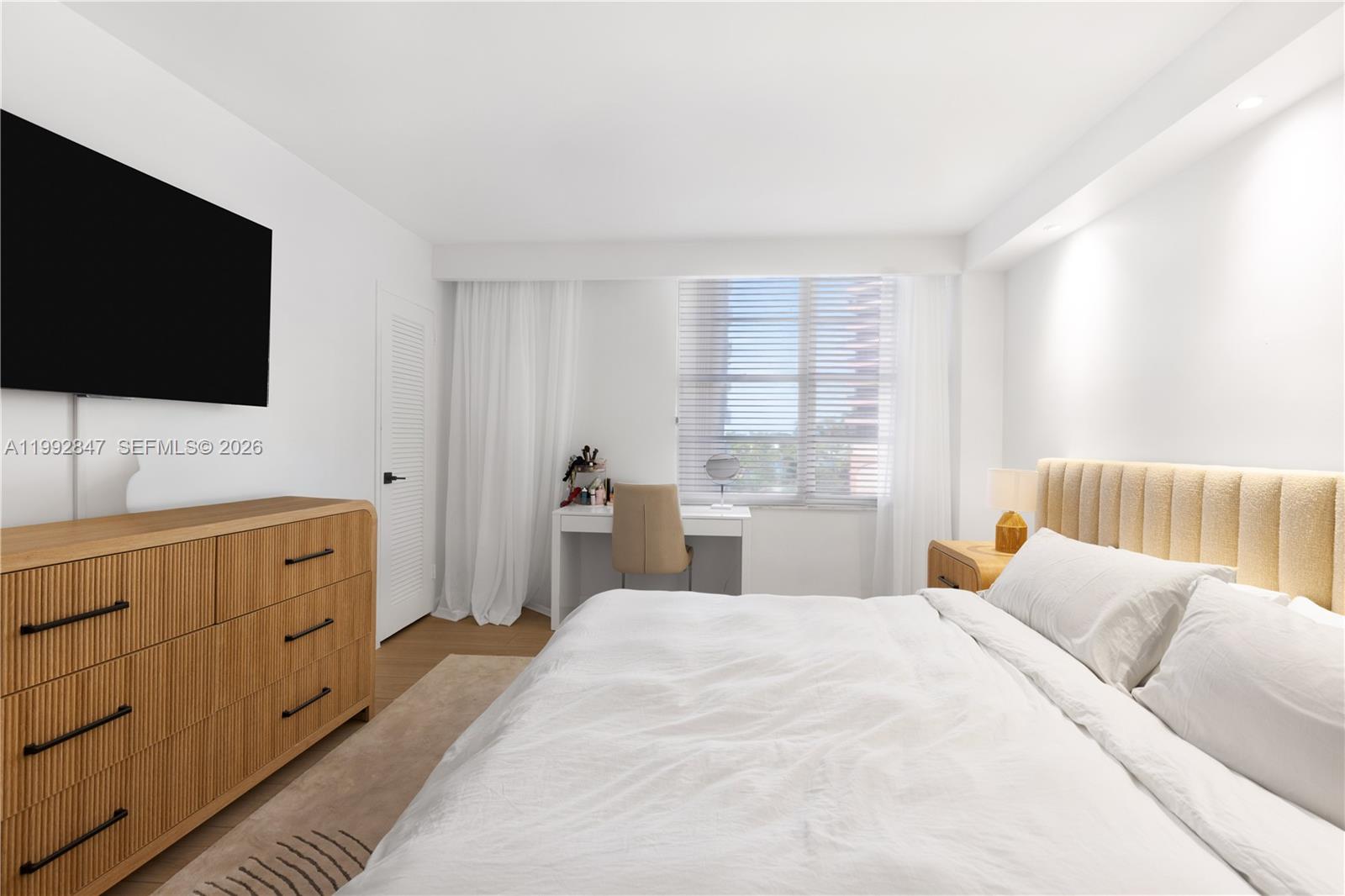 A bedroom features a light wood dresser, a bed with a tufted headboard, and a desk — 5161 Collins Ave # 410, Miami Beach FL 33140, MIAMI BEACH, FL