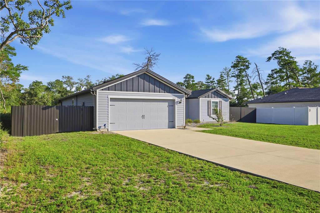 A single-story house with a gray garage, light blue siding, and a concrete driveway — 3125 SW 172ND LANE ROAD, OCALA, FL
