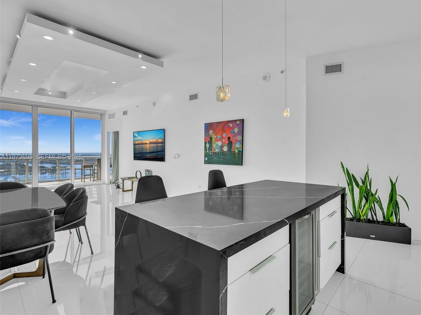 A modern kitchen island with a black marble countertop sits in a bright, open-plan room — 2020 N Bayshore Dr # 3303, Miami FL 33137, MIAMI, FL