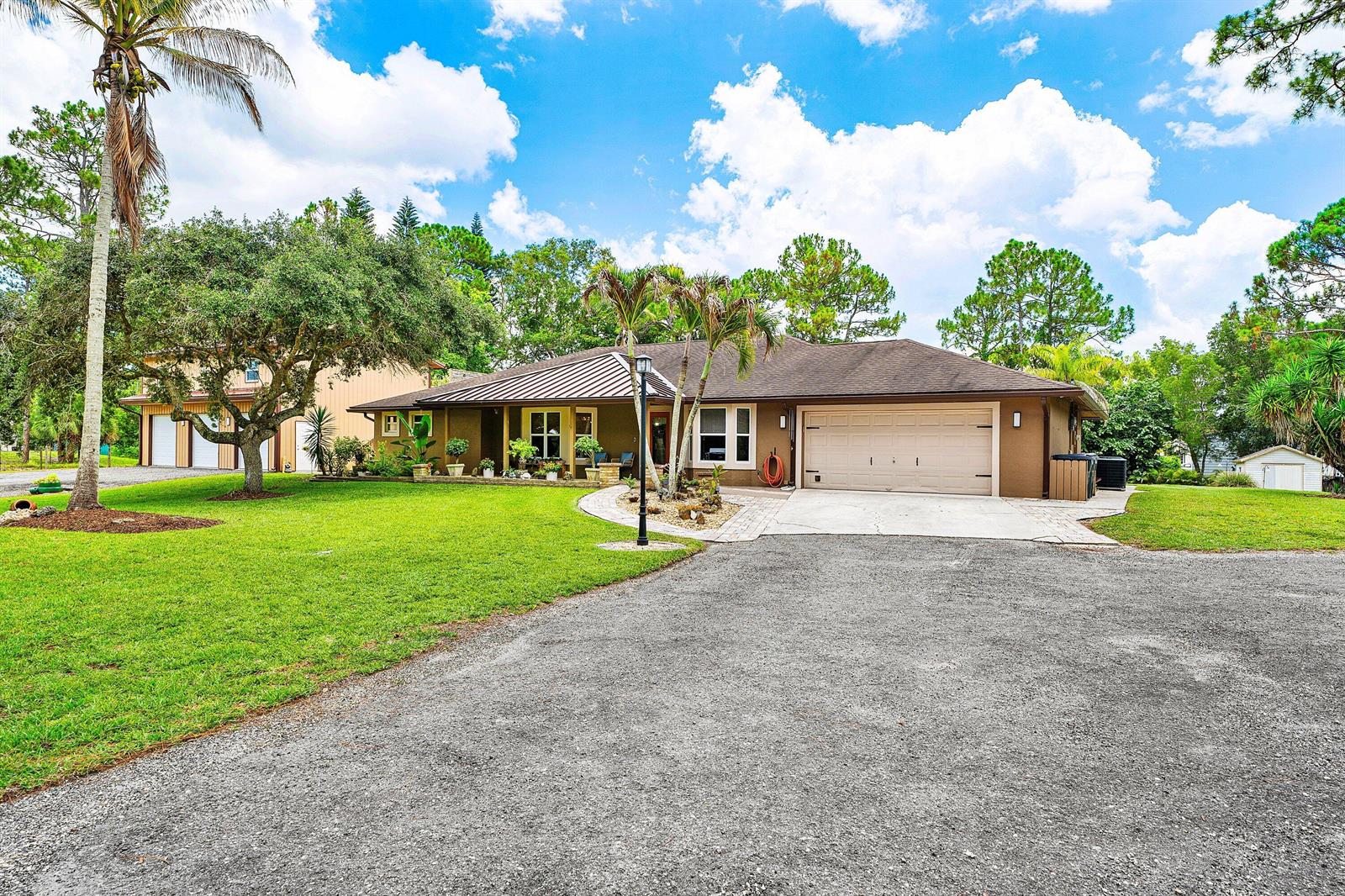 A brown single-story house with a metal roof, attached garage, and a large front lawn — 14732 63rd Court N, Loxahatchee FL 33470, LOXAHATCHEE, FL