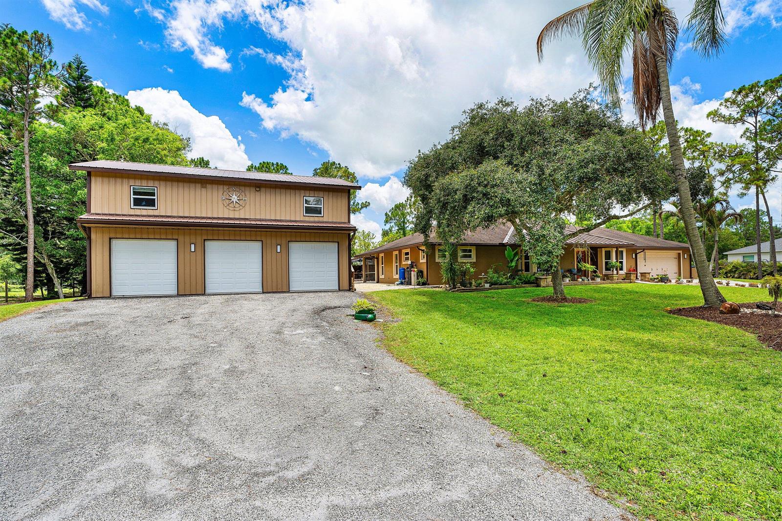 A detached three-car garage stands beside a single-story house on a gravel driveway — 14732 63rd Court N, Loxahatchee FL 33470, LOXAHATCHEE, FL