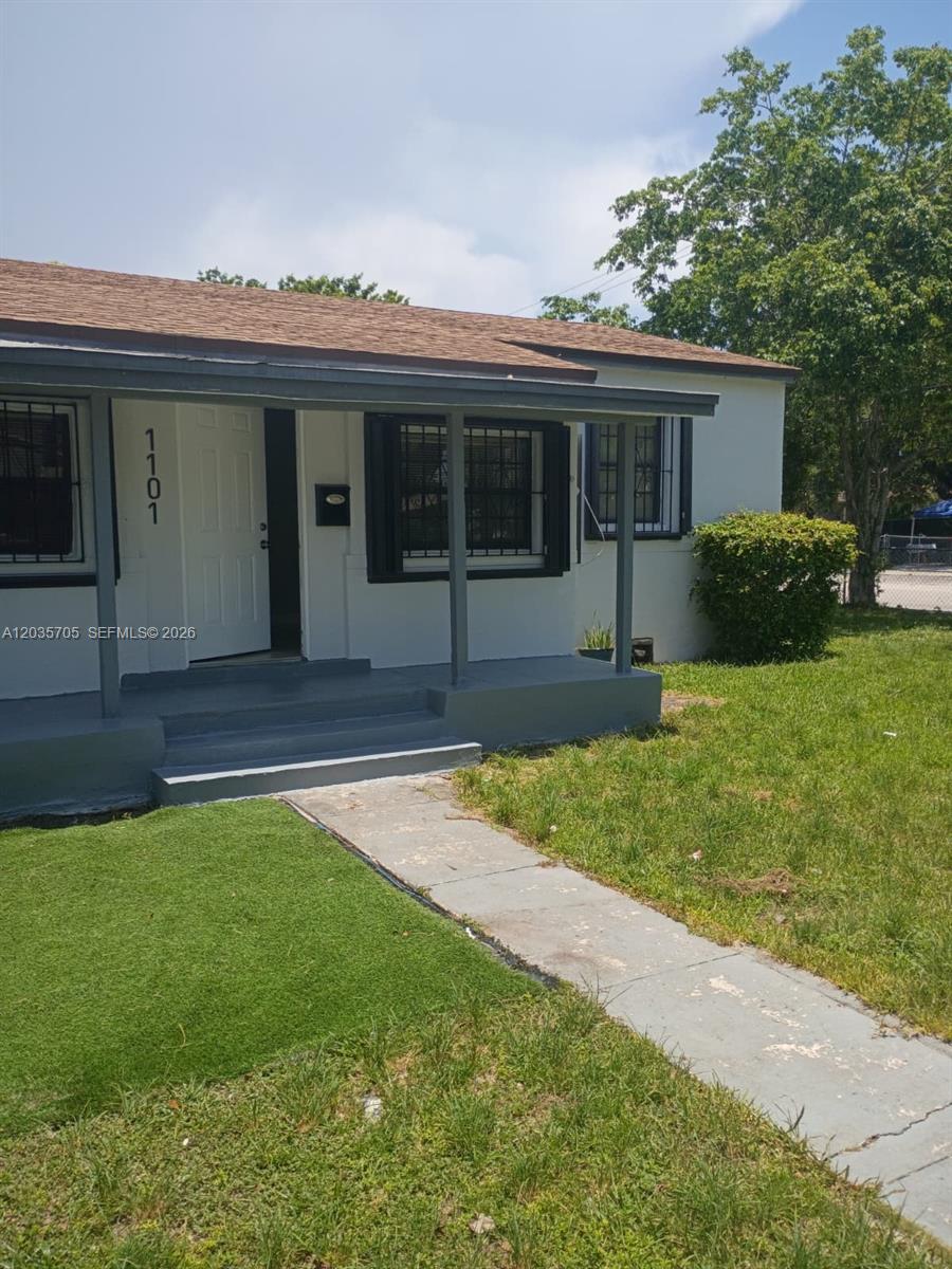 A single-story house with a covered front porch, white exterior walls, and dark trim — 1101 NW 55th Ter, Miami FL 33127, MIAMI, FL