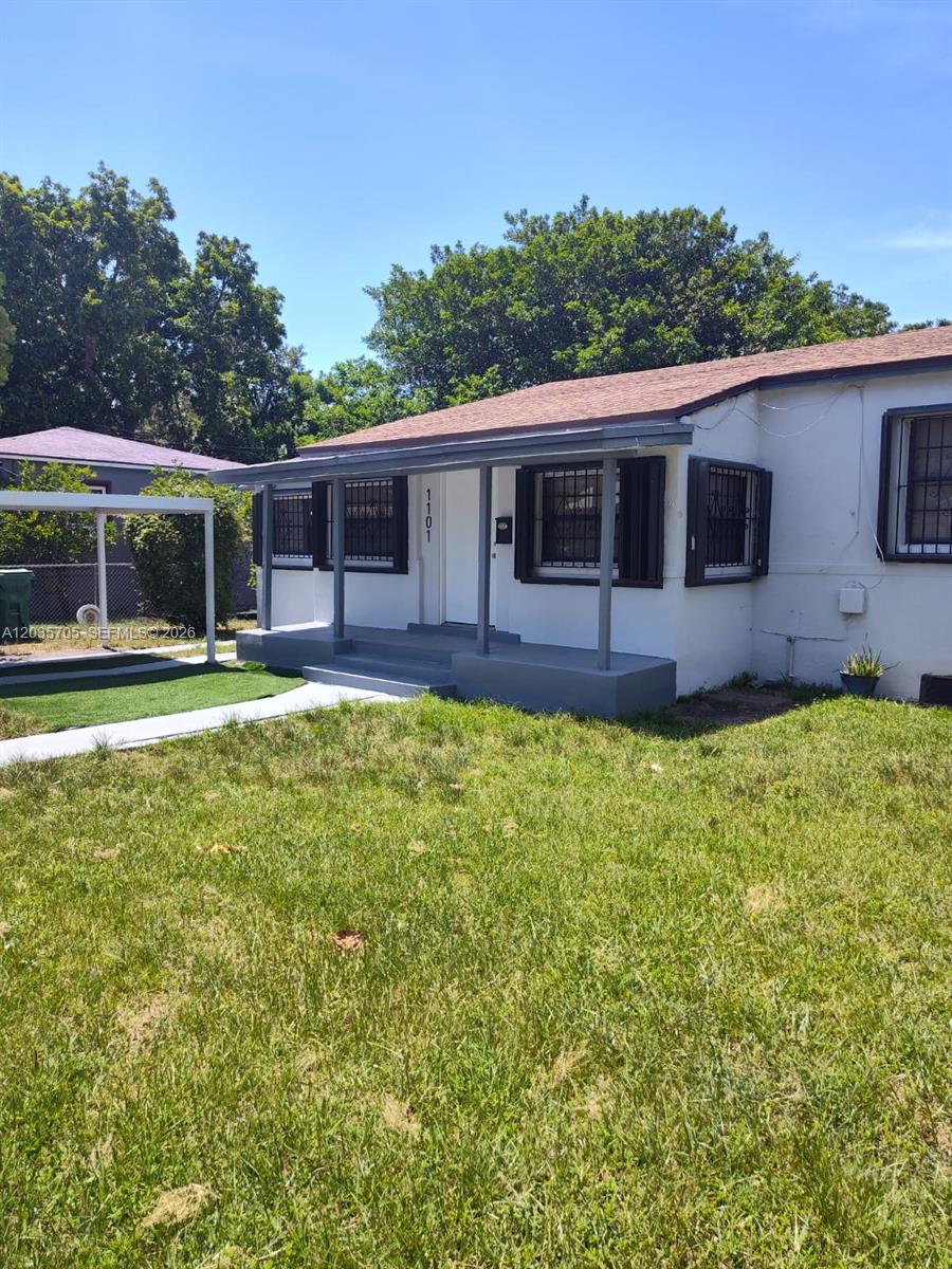 A single-story house with a covered front porch, white siding, and dark window shutters — 1101 NW 55th Ter, Miami FL 33127, MIAMI, FL