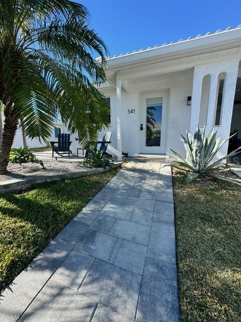 A stone walkway leads to the front entrance of a white house with a palm tree — 541 SPANISH DRIVE N, LONGBOAT KEY, FL