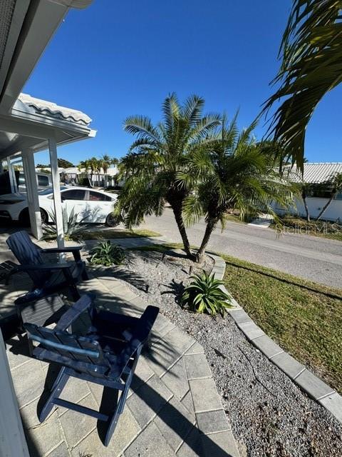 A paved patio features two blue chairs and a small palm tree under a clear sky — 541 SPANISH DRIVE N, LONGBOAT KEY, FL