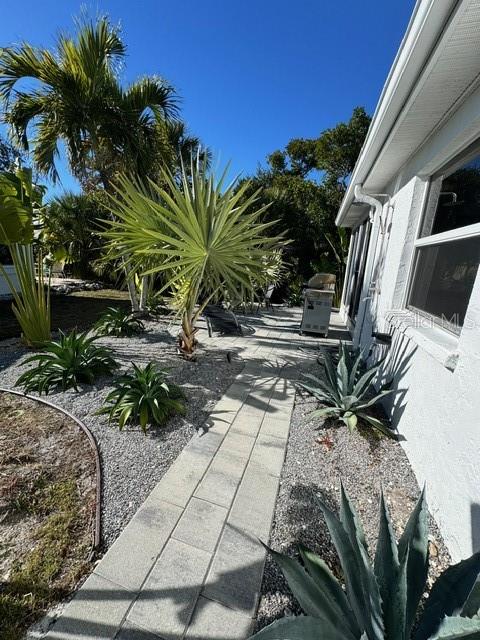 A paved walkway leads alongside a white house exterior with palm trees and agave plants — 541 SPANISH DRIVE N, LONGBOAT KEY, FL