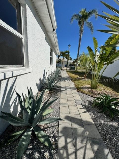 A paved walkway runs alongside a white house exterior with agave plants and palm trees — 541 SPANISH DRIVE N, LONGBOAT KEY, FL
