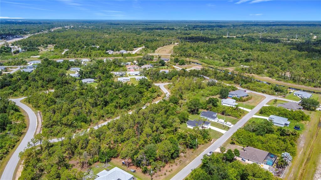 An aerial view shows a suburban neighborhood with scattered houses surrounded by dense green trees — LISA BOULEVARD, NORTH PORT, FL