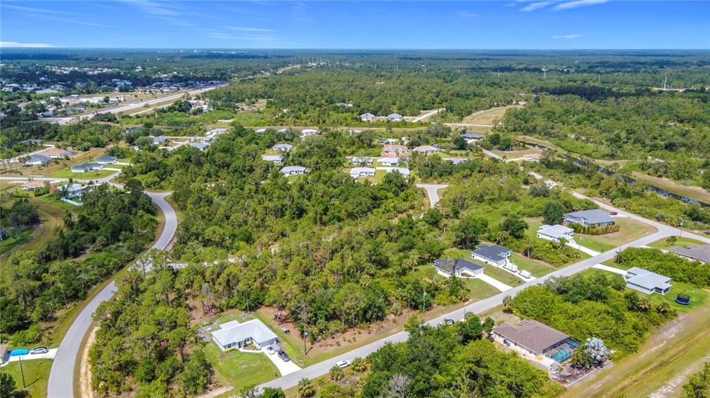 An aerial view shows a residential neighborhood with houses surrounded by dense green trees — LISA BOULEVARD, NORTH PORT, FL