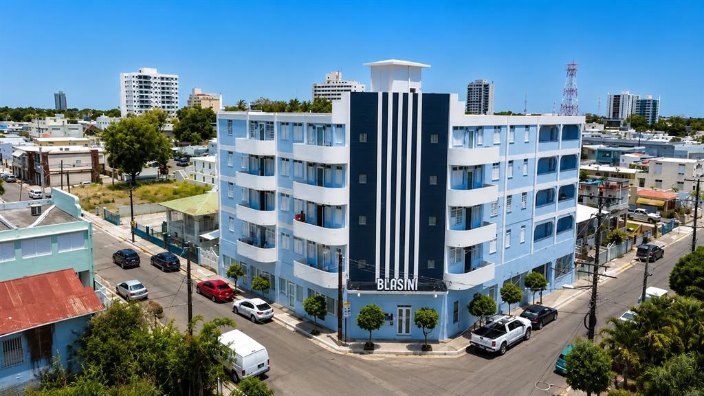 An aerial view of a light blue, multi-story Art Deco apartment building on a corner lot — 2844 ROOSEVELT UNIT 302, PONCE, PR