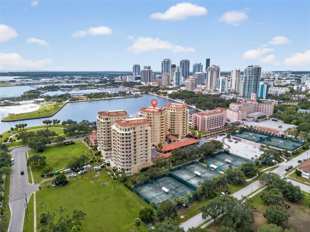 An aerial view of a multi-story apartment complex with tennis courts near a waterfront — 555 5TH AVENUE NE UNIT 332, ST PETERSBURG, FL