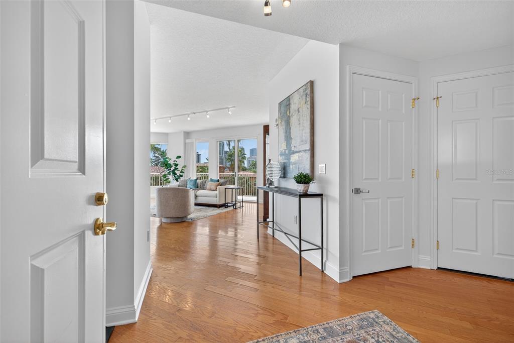 An entryway with hardwood floors leads into a bright living room with a balcony view — 555 5TH AVENUE NE UNIT 332, ST PETERSBURG, FL