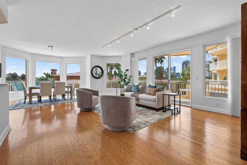 A living and dining area with hardwood floors, large windows, and a balcony overlooking city buildings — 555 5TH AVENUE NE UNIT 332, ST PETERSBURG, FL