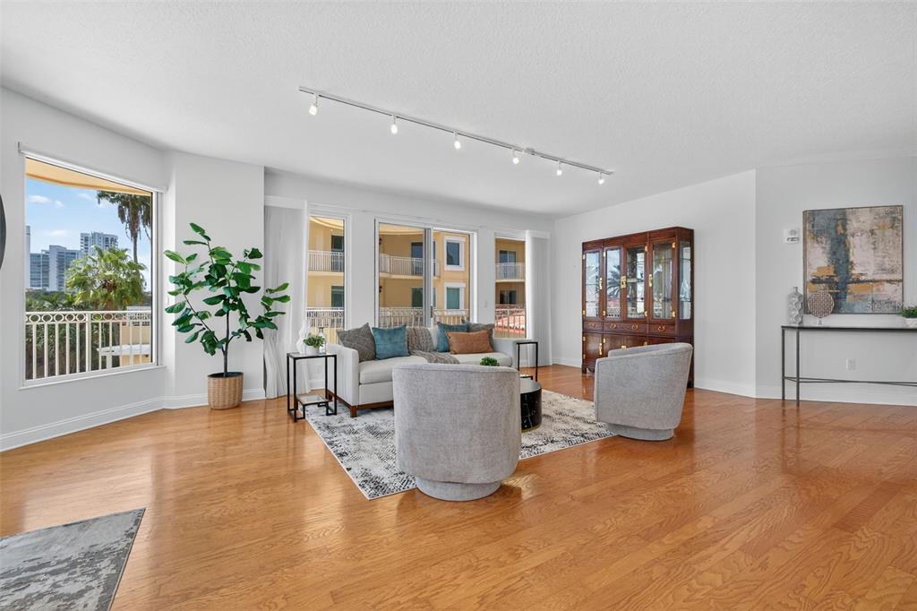 A living room features hardwood floors, a track lighting system, and a view of balconies — 555 5TH AVENUE NE UNIT 332, ST PETERSBURG, FL