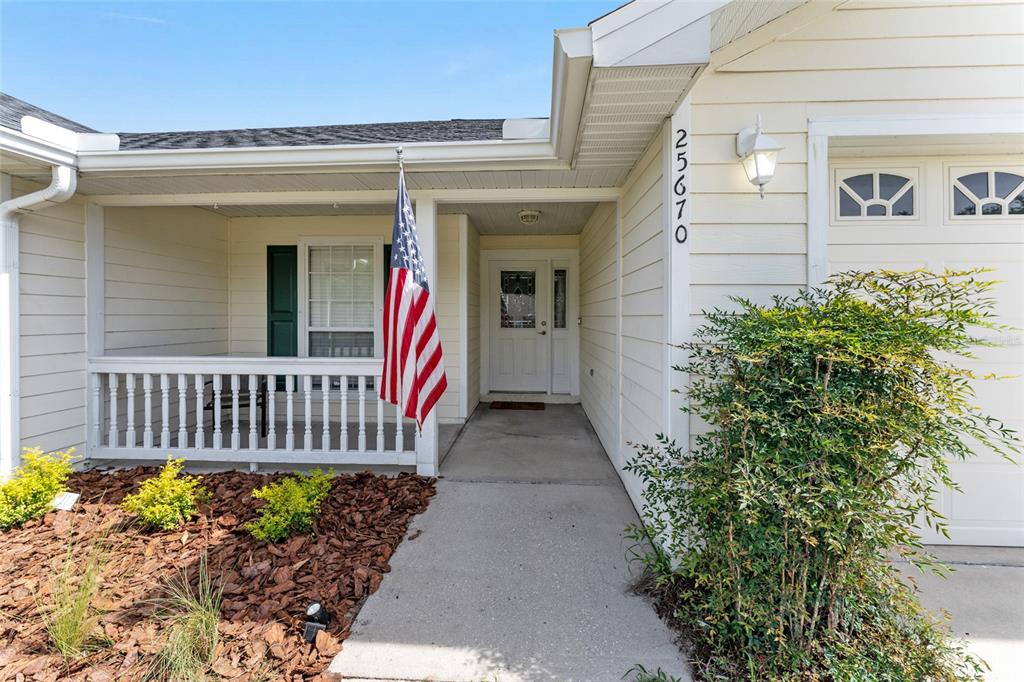The exterior of a house features a covered porch, a front door, and a garage — 25670 NW 9TH ROAD, NEWBERRY, FL