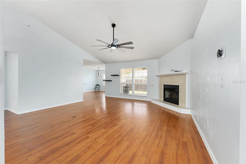 A living room with wood-look flooring, a ceiling fan, and a corner fireplace — 25670 NW 9TH ROAD, NEWBERRY, FL