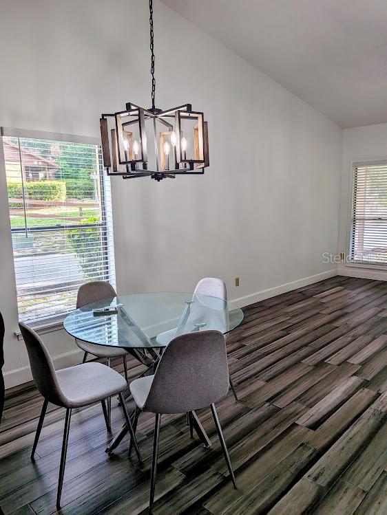 A dining area features a glass-top table, four gray chairs, and a modern geometric chandelier — 1021 LOVE LANE UNIT 39, APOPKA, FL